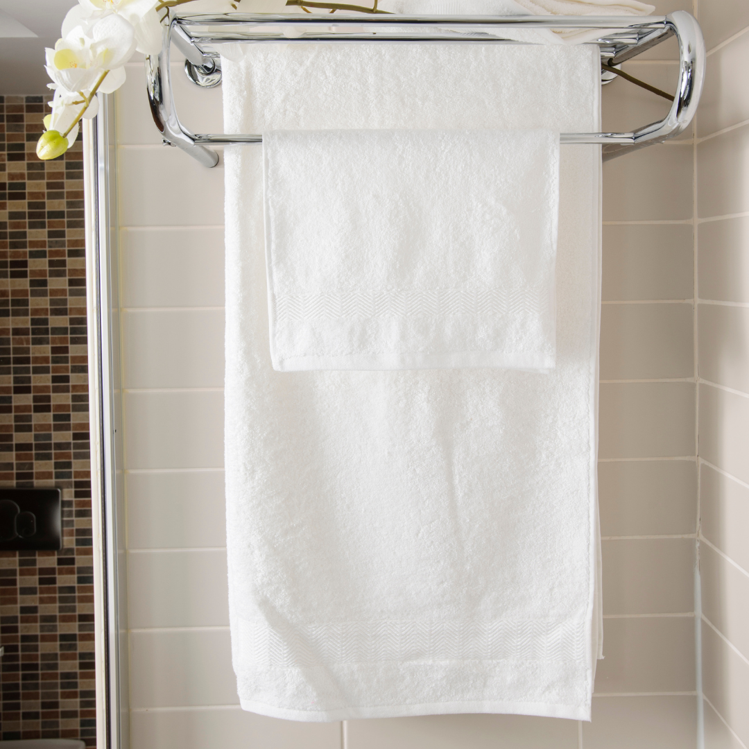 A neatly folded organic cotton towel in a soft, natural shade, with a smooth, plush texture. The towel lies on a wooden surface, radiating a sense of warmth and luxury. Nearby, a hint of greenery adds a touch of nature, highlighting the towel’s eco-friendly, sustainable origins, perfect for a relaxing, spa-like self-care experience