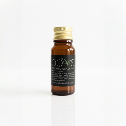 Bottle of organic scalp oil with a gold cap on a white background