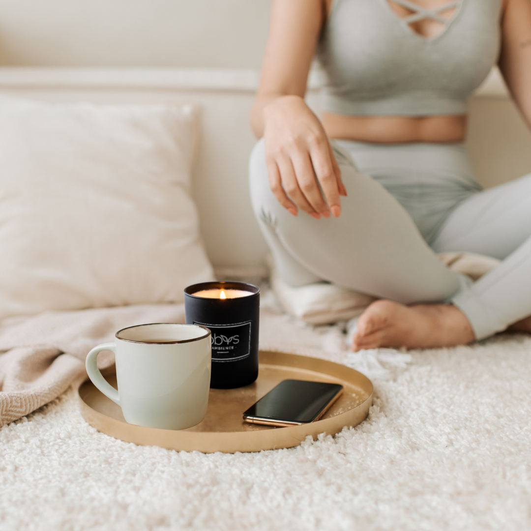 A matte black candle jar filled with organic essential oils, burning with a soft, warm flame. The minimalist design exudes elegance, while the gentle aroma from natural essential oils creates a calming, eco-friendly atmosphere. The candle sits on a wooden surface, with subtle shadows enhancing its luxurious, earthy vibe, perfect for relaxation or meditation