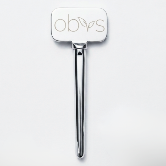 A polished silver metal hair tool with a rectangular head engraved with the brand name 'obvs' and a small leaf motif, shown on a clean white background.