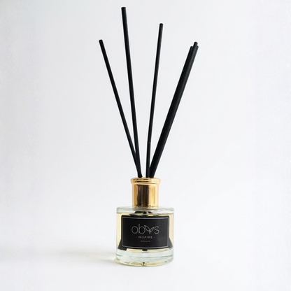 Reed diffuser with black sticks in a glass bottle on a white background