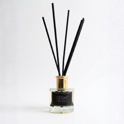 Reed diffuser with black sticks in a glass bottle on a white background