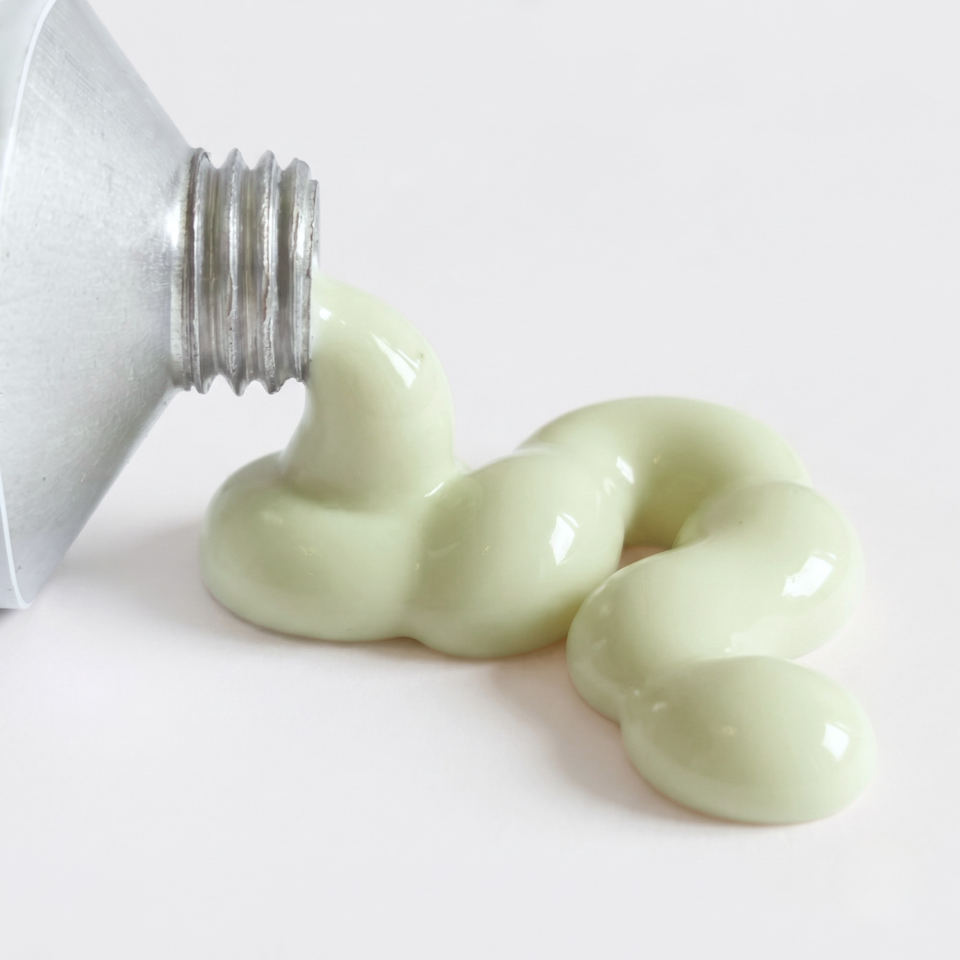A close-up of spf being squeezed from a silver tube onto a clean white surface.