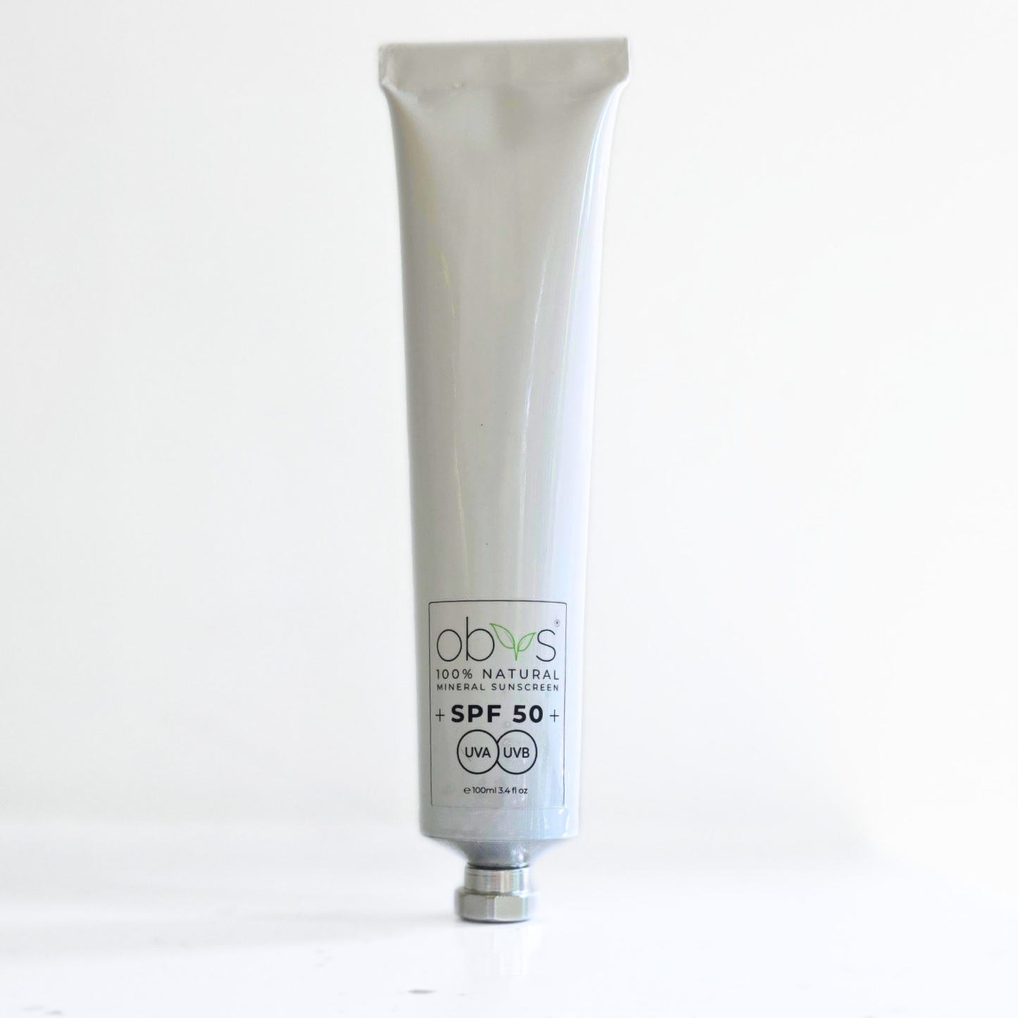 A white squeeze tube of obvs 100% Natural Mineral Sunscreen SPF 50+ with a silver cap, standing upright on a white surface against a white background.