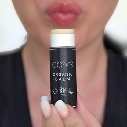Person holding an organic balm stick with 'obvs' branding